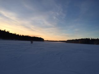 Kaksi hiihtäjää Rehjansalmella auringonlaskussa