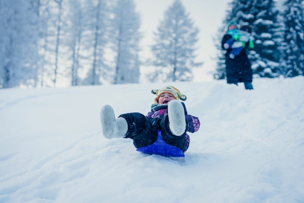 A happy child sliding down a hill in winter.