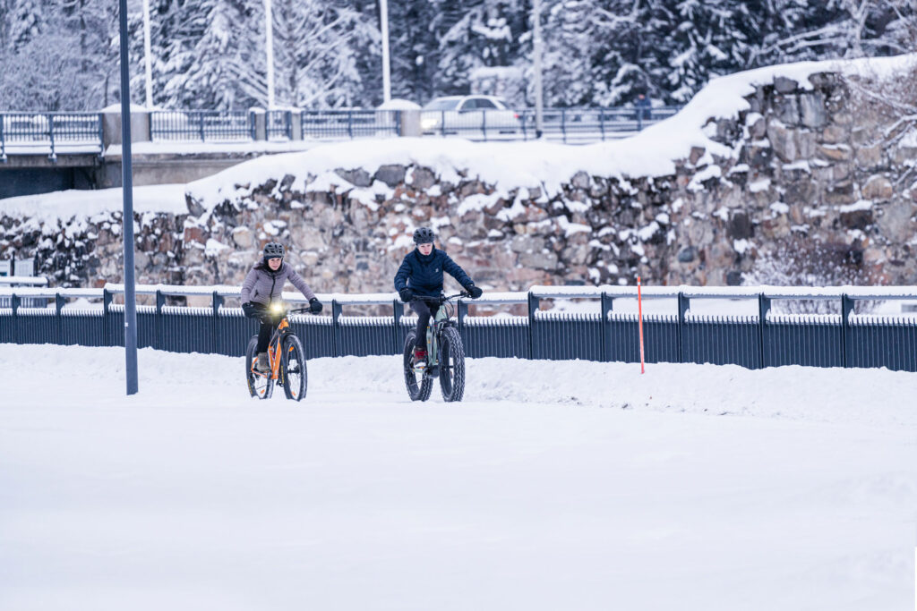 Kaksi talvipyöräilijää, takana rauniolinna